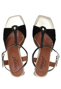 Schwarze und metallisch silberne High Heels mit eckiger Spitze, Knöchelriemen und einer Schlaufenakzent. Wildleder- und glatte Lederstrukturen.