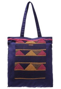 Textilaxelväska med lila tygkropp, försedd med en mönstrad vävd panel i guld, rosa och blå trianglar. Dubbel tyghandtag.