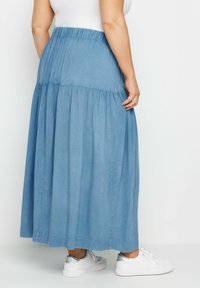 Ljusblå, lager-på-lager maxikjol i mjukt tyg med elastisk midja. Matchas med vita sneakers med silverdetaljer.