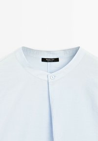 Lichtblauwe, korte mouwen shirt met een ronde halslijn, een enkele knoopsluiting en een zachte, gestructureerde stof. Merkal van het merk zichtbaar.