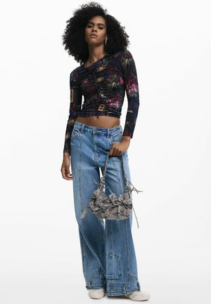 Long-sleeve black top with colorful floral patterns, paired with light blue wide-leg jeans. Gray handbag with floral accents and a textured finish.