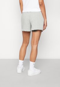 Shorts en coton gris avec un ourlet retroussé, associés à des chaussures et des chaussettes de sport blanches. Le design est décontracté avec une taille élastique.