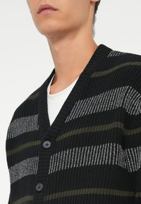 Black knit cardigan with horizontal stripes in gray and olive green, featuring a V-neck, three buttons, and ribbed texture.
