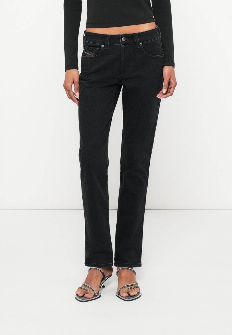 Čierne džínsy z denimu s rovnými nohavicami, piatimi vreckami a kontrastným šitím. Nosia sa s sandálmi na vysokom podpätku so remienkami.