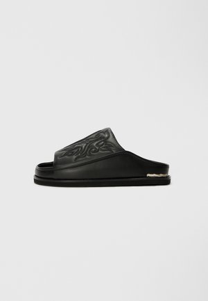 Black slide sandal made of smooth leather, featuring an embossed swirl pattern on the upper, flat sole, and minimal hardware detail.