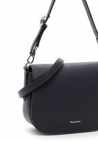 Tamsiai mėlynos tekstūruotos odos kryžminė rankinė. Yra nuimamas diržas, sidabrinės spalvos detalės ir logotipo akcentas priekyje.