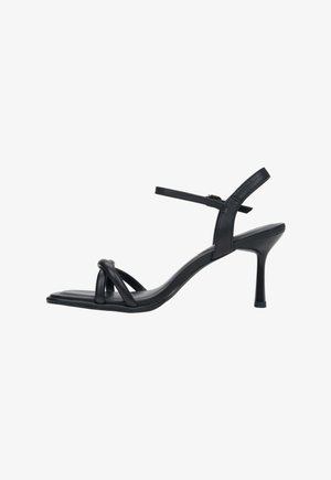 Czarne sandały na obcasie z kwadratowym noskiem i cienkimi paskami, zawiązane w supeł na przodzie stopy, na szpilce.