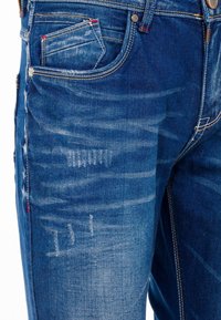 Blauwe denim jeans met een licht vervaagde afwerking, contrasterende stiksels, zakken aan de voorkant en versleten accenten op het dijbeen.
