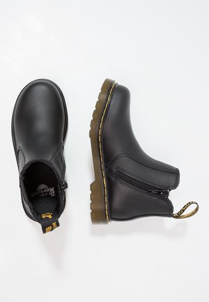 Black leather ankle boots with side zipper, yellow stitching on brown rubber sole, and branded pull tab on heel loop.