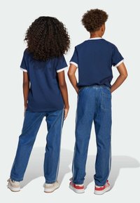 Ναυτικά μπλε μπλουζάκια με λευκά μανίσια συνδυασμένα με μπλε τζιν παντελόνια που έχουν ρίγες στο πλάι. Αθλητικά παπούτσια σε ήπιους τόνους ολοκληρώνουν την εμφάνιση.