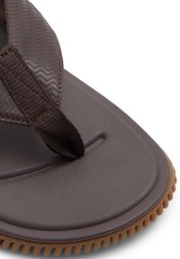 Ruskot ruskea muoviflip-flop, jossa on teksturoitu tummanruskea hihna ja paksu, uritettu vaaleanruskea pohja. Sisältää keskeisen varpaankohdan ja tasaisen jalkapohjan.