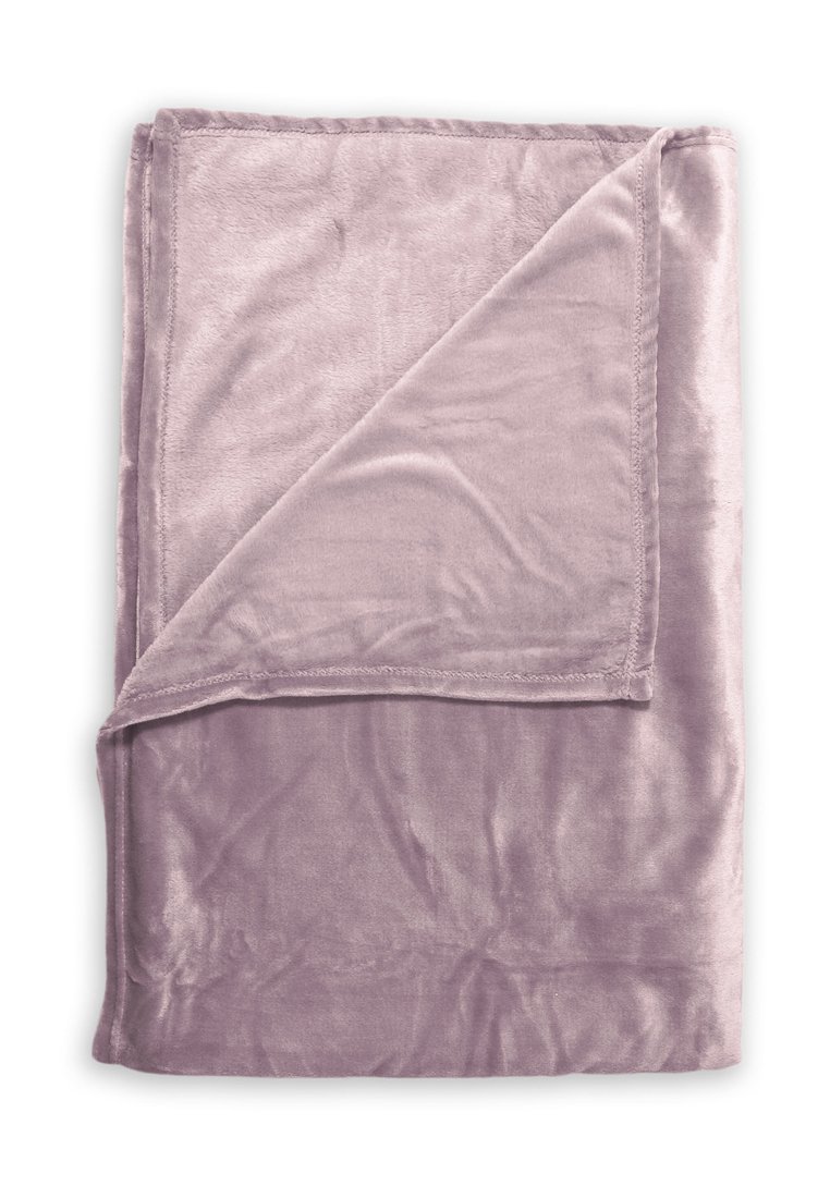 Manta de terciopelo suave plegada en un suave color malva con una esquina doblada, mostrando una textura lisa y bordes cosidos.