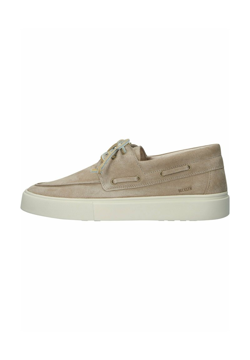 Chaussure en daim beige clair au design bas, avec un bout arrondi, des lacets et une semelle en caoutchouc blanche. Des coutures discrètes sont visibles.