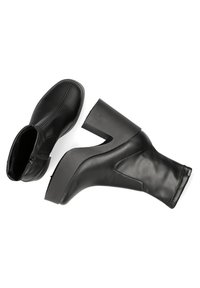 Botas negras hasta el tobillo con un diseño elegante, hechas de cuero suave. Presenta un tacón triangular y cierre de cremallera. Estilo minimalista y contemporáneo.