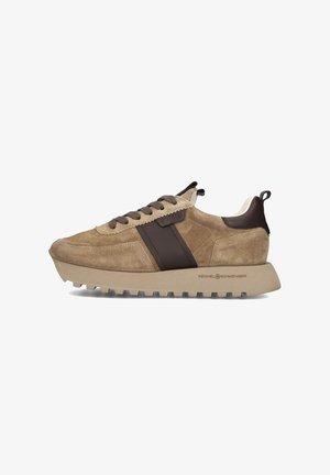 Tan suede sneaker with thick beige ridged sole, dark brown leather strip, brown laces, and pull tab at heel, side view on white background.