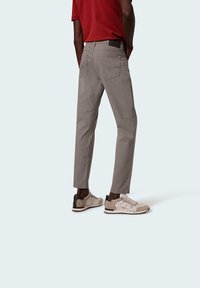 Light gray pants made of textured fabric, featuring a slim fit, back pockets, and a black accent on the waistband. Paired with patterned sneakers.