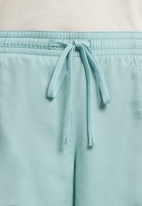 Helle blaue Jogginghosen mit einem elastischen Bund und passendem Kordelzug, aus weichem Stoff mit glatter Textur.