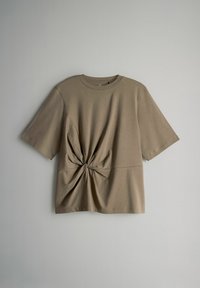 Lühikeste varrukatega oliivroheline T-särk, mis on valmistatud pehmest puuvillast, ning millel on sõlmpunkt vöökohtades ja lahedam lõige. Sile tekstuur.