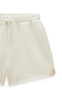 Cremefarvede shorts med et tekstureret mønster, elastisk talje med snøre og sidelommer. Sømmene har lette sideslids.