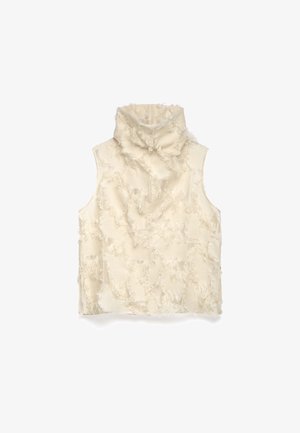 Haut à col roulé sans manches en crème, présentant une surface texturée avec des détails effilochés. Tissu doux avec une coupe ample, sans fermetures ni embellissements.