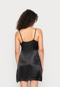 Vestido escorregadio de cetim preto com alças ajustáveis finas. Textura suave, comprimento acima do joelho e silhueta A simples. Sem enfeites.