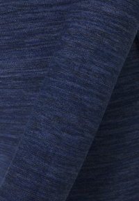 Tissu bleu foncé à texture variée. Le tissu présente un motif chiné subtil et est roulé, mettant en valeur la douceur du tissu.