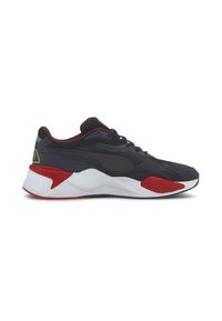 Baskets basses noires et rouges avec semelle blanche, laçage à l’avant et logo jaune en forme de triangle près du talon.