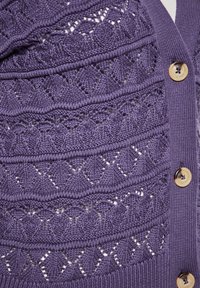Cardigan lavorato a maglia in viola con texture traforata e motivi decorativi. Presenta bordi a coste e grandi bottoni dorati.