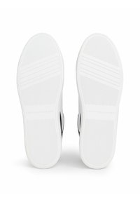 Białe podeszwy sportowe z teksturowanym wzorem antypoślizgowym, charakteryzujące się minimalistycznym designem i wytłoczonym logo "TOMMY HILFIGER" na spodzie.