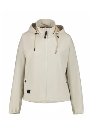Veste couleur crème en tissu doux et lisse. Dotée d'une capuche, d'une fermeture éclair sur le devant, de cordons réglables et de deux poches latérales avec fermetures à pression.