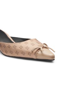 Μπεζ επίπεδη γόβα με μυτερή μύτη, υφασμάτινη υφή με σχέδιο λογότυπου και διακοσμητικό φιόγκο μπροστά. Λείο δερμάτινο επικαλυμμένο άκρο μύτης.