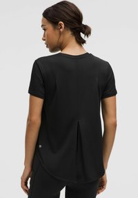 Zwarte t-shirt met korte mouwen, voorzien van een gebogen zoom, plooi-detail aan de achterkant en een zachte, gladde stoftextuur.