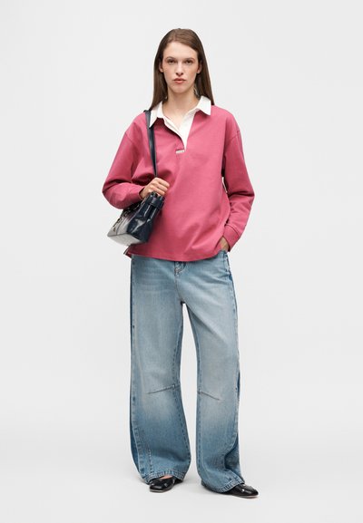 Ροζ φούτερ με λευκό γιακά, άνετη εφαρμογή, συνδυασμένο με φαρδιά ανοιχτό μπλε τζιν και μικρή μαύρη τσάντα. Ομαλές υφές παντού.