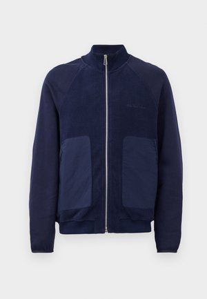 Chaqueta azul marino con cremallera que presenta una mezcla de tela suave y texturada, dos bolsillos frontales y un cuello alzado.