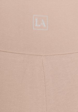 Beige knit fabric with vertical seam and white "LA" letters enclosed in a square centered near the top.