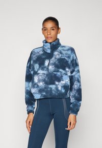 Blue and black fleece pullover with high collar, quarter-zip front, and textured, cloud-like pattern; paired with navy leggings featuring dotted accents.