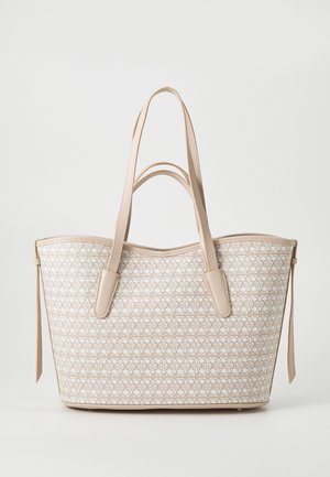 Bolso tote beige y blanco con patrón geométrico, con dos asas largas y lazos laterales, sobre un fondo liso.