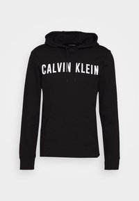 Sudadera negra hecha de una suave mezcla de algodón, con un bolsillo tipo canguro y el texto blanco "CALVIN KLEIN" en el pecho. Capucha con cordón.