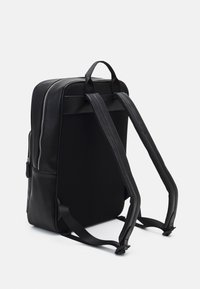 Zaino nero con una parte anteriore in pelle liscia e un retro in rete testurizzata. Presenta spallacci imbottiti e una chiusura centrale a zip.