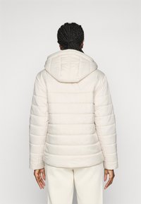 Puffer jacket in light beige, featuring a hood, quilted design, and soft texture. The sleeves are cuffed and the bottom hem is straight.