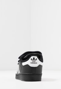 Mustat lenkkarit valkoisilla yksityiskohdilla, valmistettu nahasta. Varustettu kolmella valkoisella raidalla ja tekstuurilla varustetulla kumipohjalla. Sisältää logon kantapäässä.