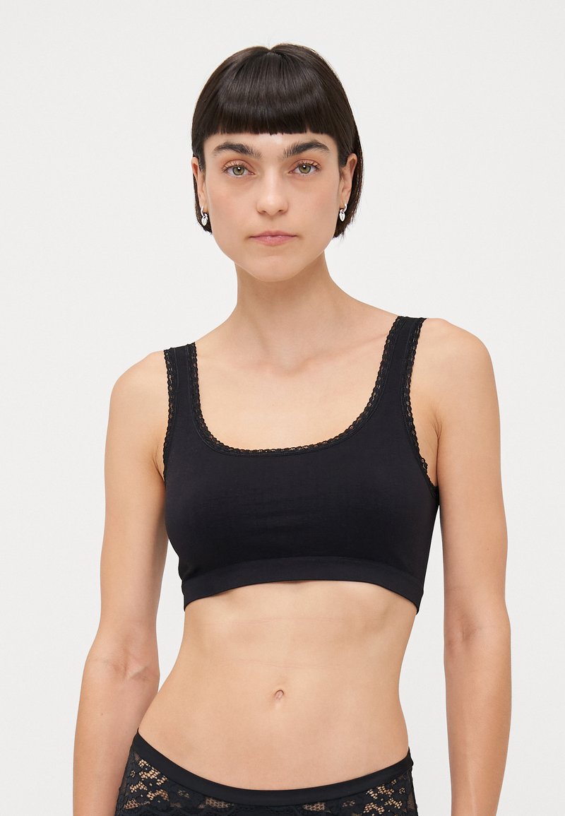 Black crop top featuring a scoop neckline and wide straps, made of a smooth fabric with lace trim accents along the neckline.