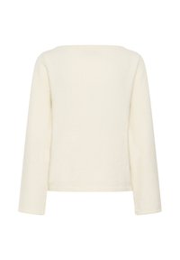 Haut blanc à manches longues avec une silhouette carrée, une texture douce et un col large. Le tissu semble chaud et légèrement texturé, sans motifs.