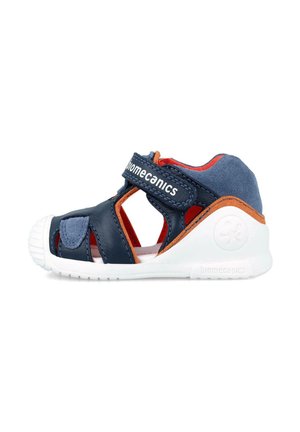 Sandali in pelle blu con ritagli, suola bianca, cinturino regolabile, fodera interna rossa e dettagli arancioni. Progettati per comfort e stabilità.