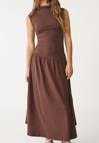 Ruskea ilmanhiha maxi-mekko, jossa on istuva yläosa, rypytetty vyötärö ja laskostettu hame. Wydhys kankaan pinta.