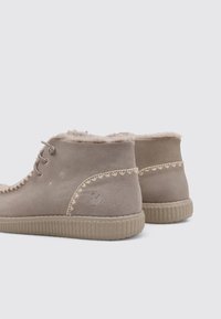Botas de tobillo de ante beige con forro de piel sintética, con costuras decorativas a lo largo del borde y una suela de goma texturizada.