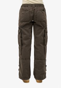 Dunkelbraune Cargo-Hosen mit mehreren Rückentaschen und Seitentaschen, lockerer Sitz, elastischer Bund, von hinten auf einem weißen Hintergrund gezeigt.