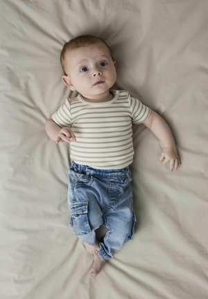 Randig kortärmad bodysuit i kräm och brunt, ihop med ljusblå denim cargo byxor. Bakgrunden är ett mjukt beige tyg.