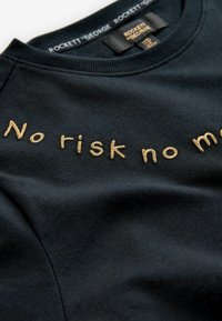 Felpa nera con collo rotondo e testo ricamato beige "No risk no m" e etichetta del marchio "ROCKETT GEORGE" all'interno del colletto.