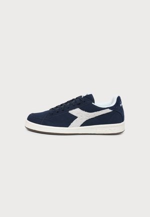 Granatowy sneaker z białym, teksturowanym paskiem z logo, białą podeszwą i sznurówkami, pokazany z profilu na jasnym tle.